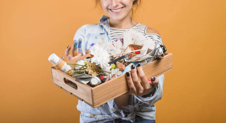 Nesta imagem, Diy faça você mesmo, uma mulher segurando uma caixa com muitas coisas aleátorias, que nós achamos que nunca vamos usar, até nos ter otímas idéias.