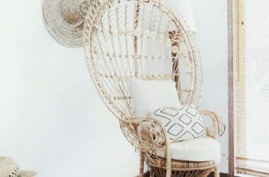 Sala de estar em estilo afro-boêmio com poltrona de vime e ráfia, almofadas em tons terrosos com estampa étnica, tapete de sisal e cesto artesanal de palha no canto