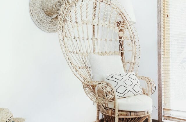 Sala de estar em estilo afro-boêmio com poltrona de vime e ráfia, almofadas em tons terrosos com estampa étnica, tapete de sisal e cesto artesanal de palha no canto