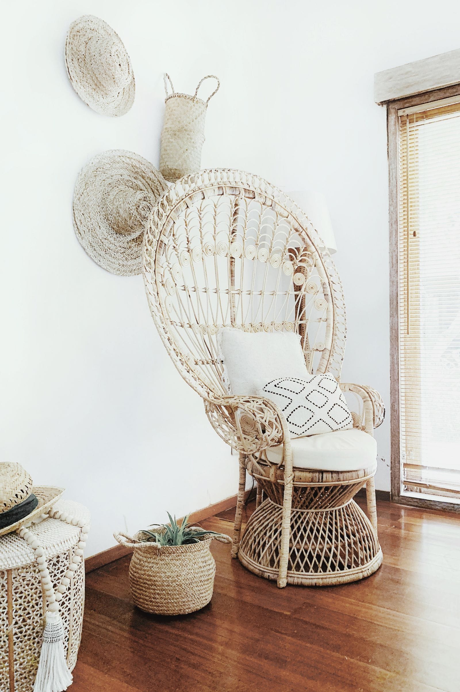 Sala de estar em estilo afro-boêmio com poltrona de vime e ráfia, almofadas em tons terrosos com estampa étnica, tapete de sisal e cesto artesanal de palha no canto