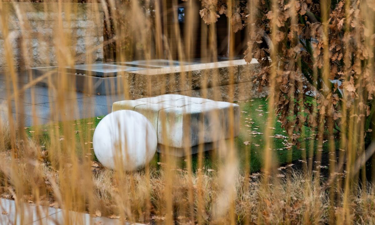 Jardim moderno e bem cuidado com banco de pedra e escultura decorativa
