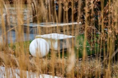 Jardim moderno e bem cuidado com banco de pedra e escultura decorativa