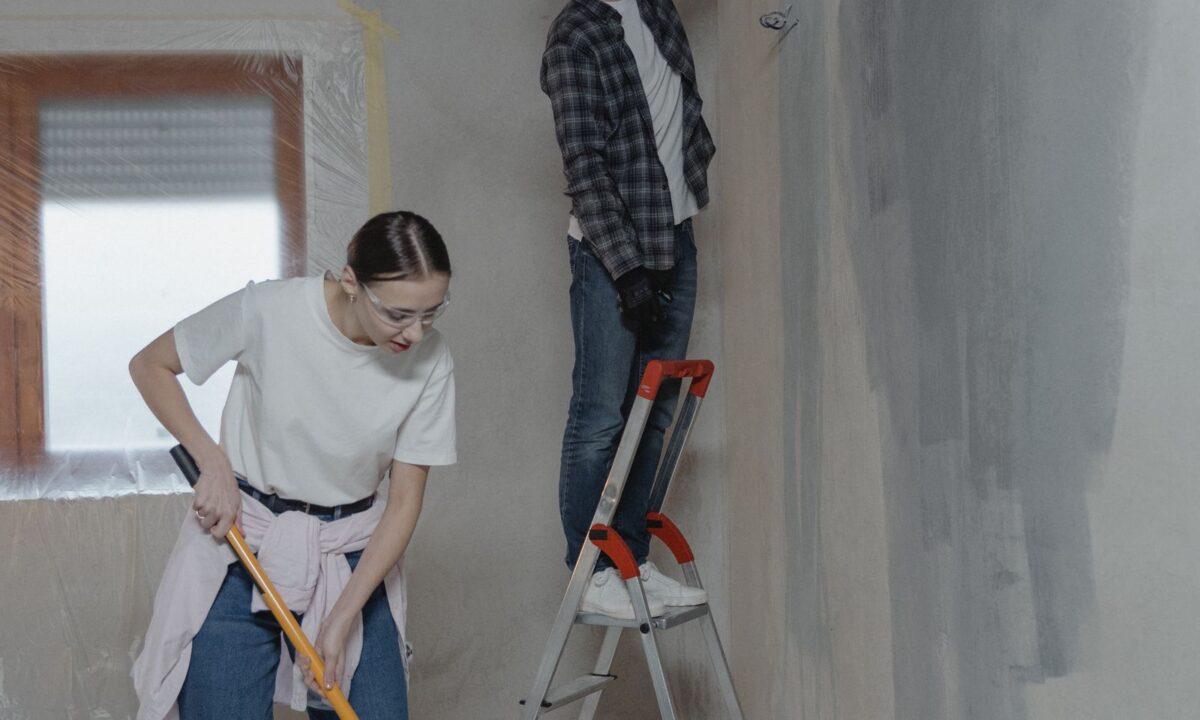 Casal pintando a parede durante uma reforma residencial de baixo custo