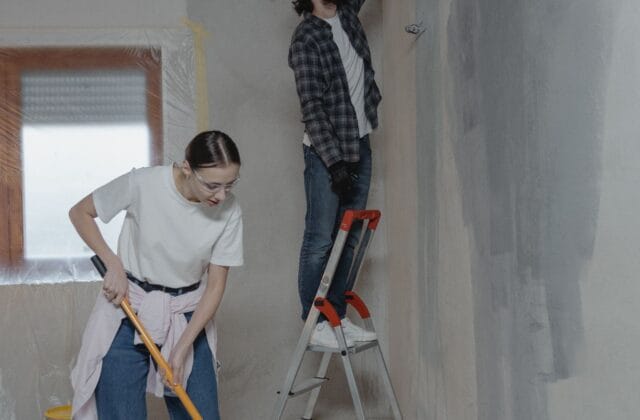 Casal pintando a parede durante uma reforma residencial de baixo custo