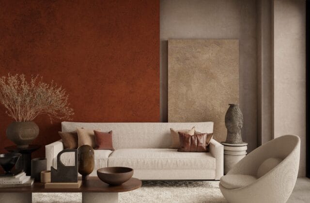 Sala de estar minimalista decorada em tons terrosos, com sofá, almofadas e parede em terracota e argila