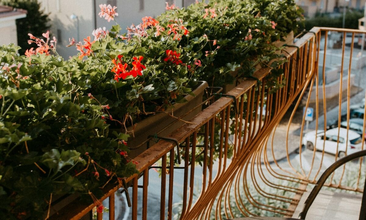 Varanda gourmet pequena decorada com flores, plantas e mesa de bistrô